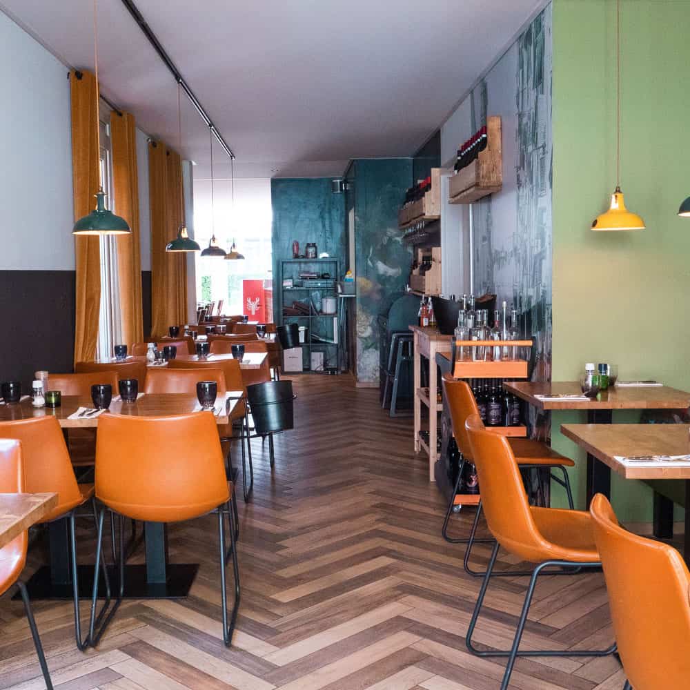 The restaurant Donato in Den Haag boasts a vibrant interior with orange chairs and green walls.